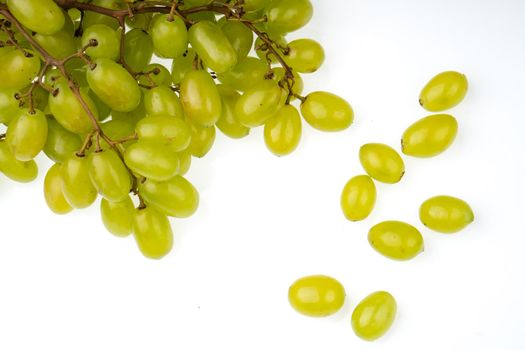 A bunch of table grapes on a white background and a bunch of white grapes scattered on a white background