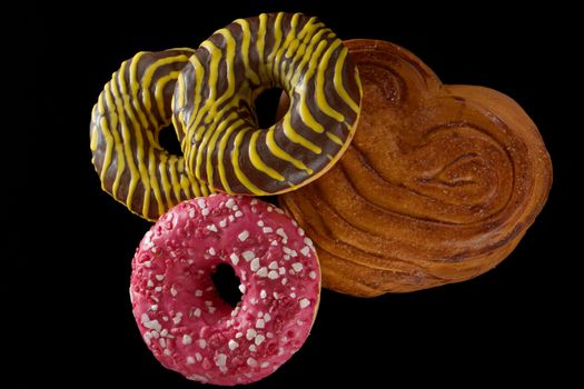 American brown and pink donuts and baked bun, on black background