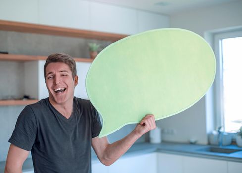 smiling man with a balloon for text standing in the new kitchen. photo with copy space