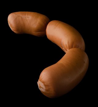 Three boiled sirloin sausages, on a black background isolated