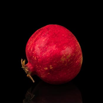 ripe whole pomegranate, on a black background isolated with reflection