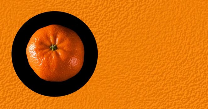 Ripe whole tangerine, on a black background, place under the text on the background of the texture of the peel of a tangerine
