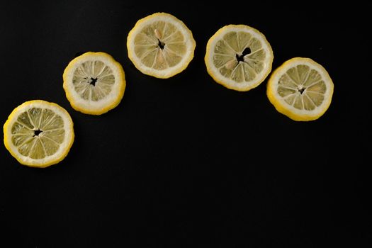 Five lemon slices lined up in a semicircle on a black background