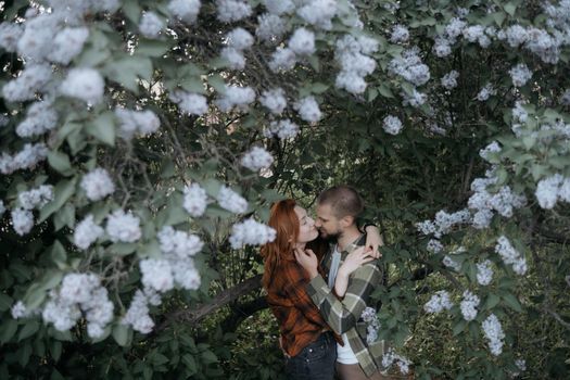 lovers embrace standing under lilacs