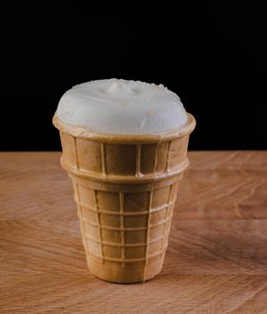 ice cream in a waffle cup on a wooden board on a scribble background