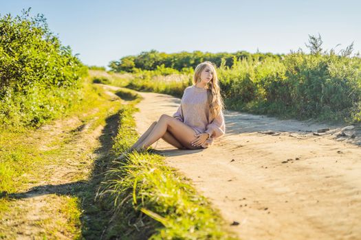 Young beautiful woman in autumn landscape with dry flowers, wheat spikes. Fashion autumn, winter. Sunny autumn, Cozy autumn sweater. fashion photo.