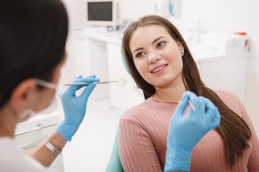 Young beautiful woman smiling at her dentist, getting dental exam