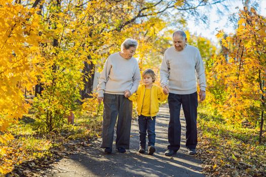 Senior couple with baby grandson in the autumn park. Great-grandmother, great-grandfather and great-grandson.