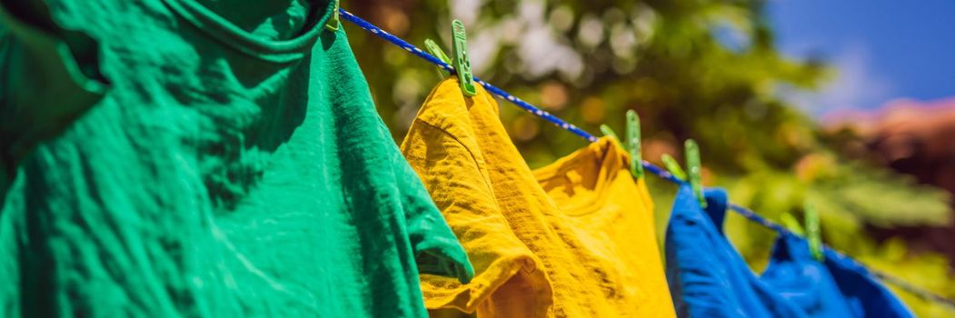 Multicolor shirts on clothesline in sunny day. BANNER, LONG FORMAT