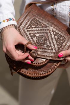 small brown women's leather bag with a carved pattern. street photo