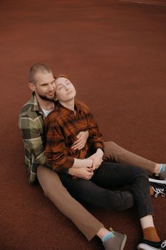 lovers sit in a hug on a red coating