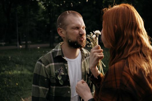 red girl blows a dandelion on her boyfriend