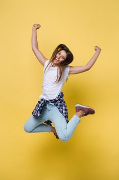 Full length portrait of a cheerful casual caucasian woman jumping isolated over yellow background.