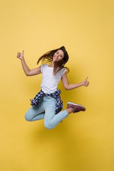 Full length portrait of a cheerful casual caucasian woman jumping isolated over yellow background.