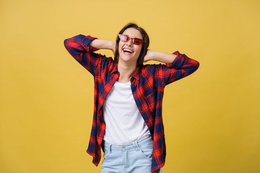 Happy stylish modern woman with modern shaped sunglasses laughing looking at you camera isolated on yellow background. Happiness concept.