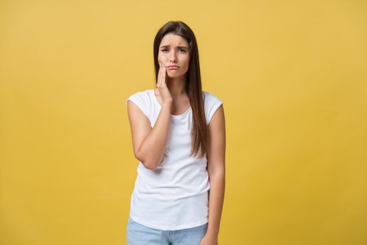 young woman has a toothache, studio photo isolated on a yellow background.