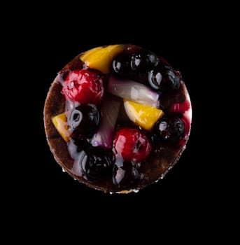 Pastry stuffed with fruits, berries and citrus fruits on a black background in isolation, view from the top, confectionery product.