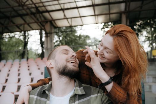 lovers fool around sitting on the stand of the stadium