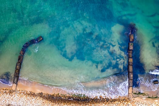 Aerial top view from drone to the seacoast and old concrete piers, Sea background.