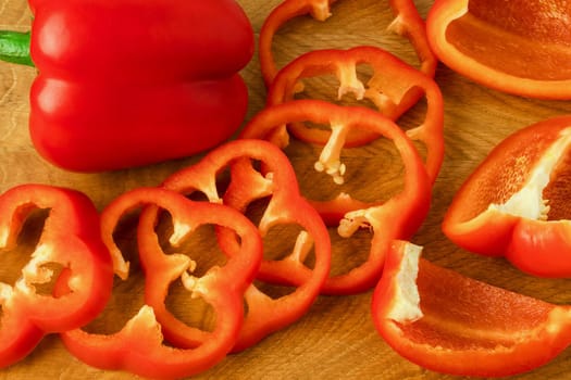 Sweet pepper, red, whole and sliced on a wooden board