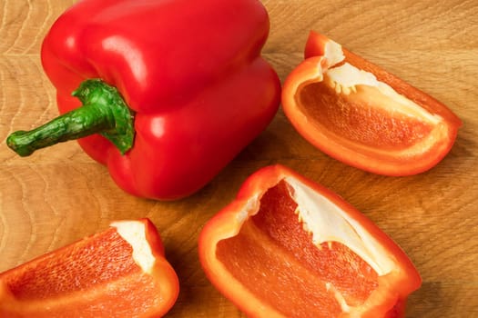 Sweet pepper, red, whole and sliced on a wooden board