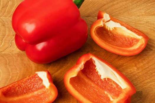 Sweet pepper, red, whole and sliced on a wooden board