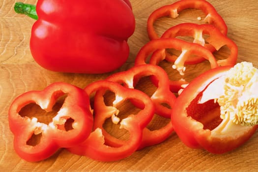 Sweet pepper, red, whole and sliced on a wooden board