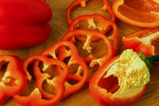 Sweet pepper, red, whole and sliced on a wooden board