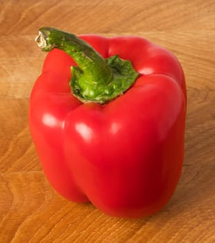 One red sweet pepper on a wooden board