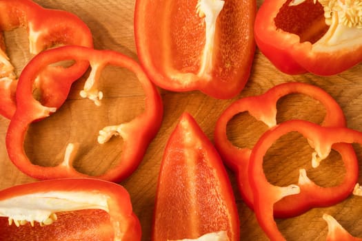 Sliced pieces, parts, lobes of sweet pepper, red, on a wooden board