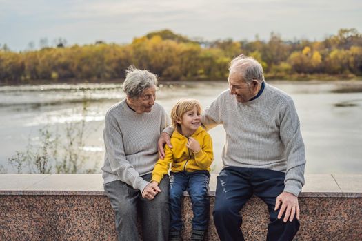 Senior couple with baby grandson in the autumn park. Great-grandmother, great-grandfather and great-grandson.