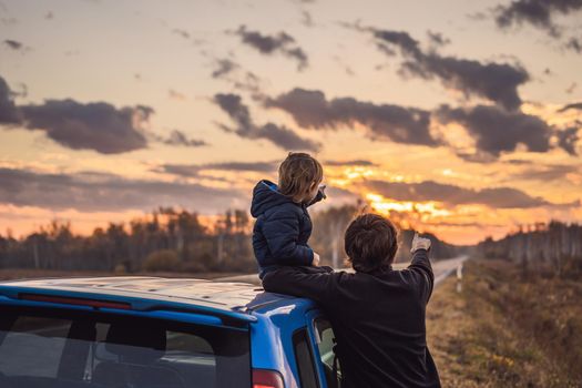 Dad and son are resting on the side of the road on a road trip. Road trip with children concept.