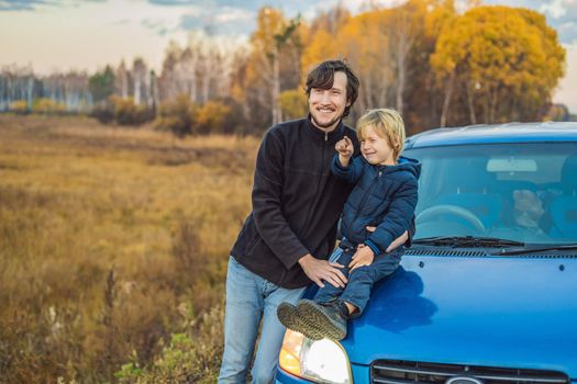 Dad and son are resting on the side of the road on a road trip. Road trip with children concept.