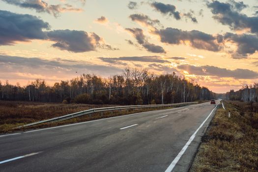 Amazing view with colorful autumn forest with asphalt mountain road. Beautiful landscape with empty road, trees and sunlight in in autumn. Travel background. Nature.