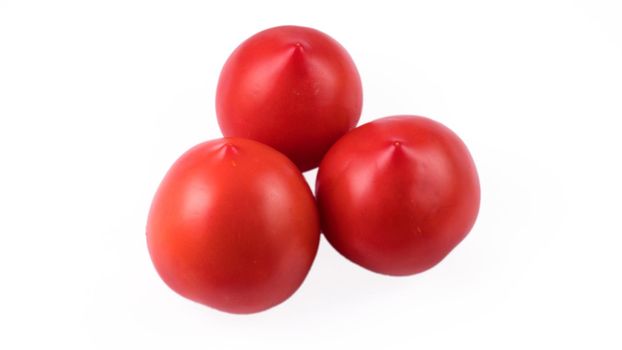 Three whole red tomatoes on a white background in isolation