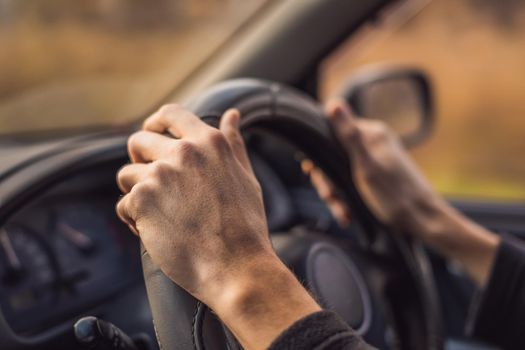 Driver's hands on steering wheel inside of a car.