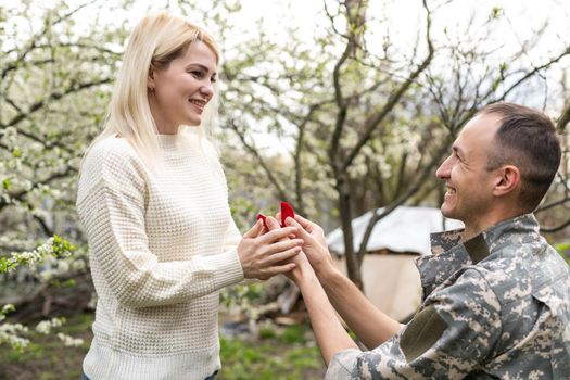 Young military couple in park showing engagement ring