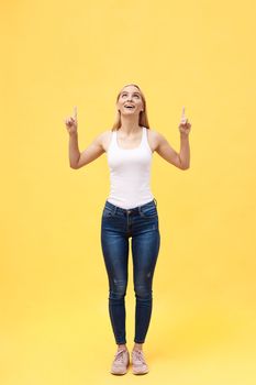 Full length portrait of successful young woman celebrating her victory. Isolated on yellow background.
