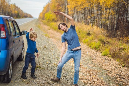 Dad and son are resting on the side of the road on a road trip. Road trip with children concept.