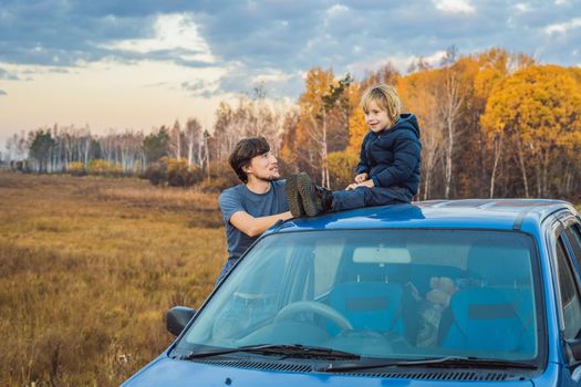 Dad and son are resting on the side of the road on a road trip. Road trip with children concept.