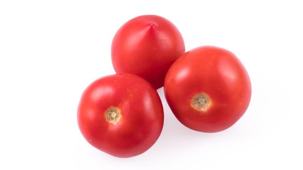 Three whole red tomatoes on a white background in isolation