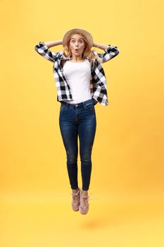 Portrait of surprised young woman in black pants jumping in front of yellow wall. Indoor portrait of young lady in fooling around in studio.