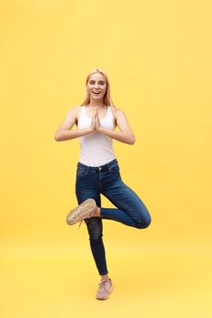 Sporty attractive young woman in white sportswear doing exercise for spine, Vrikshasana pose, hands above the head in Anjali mudra, part of large photo series, isolated, full length