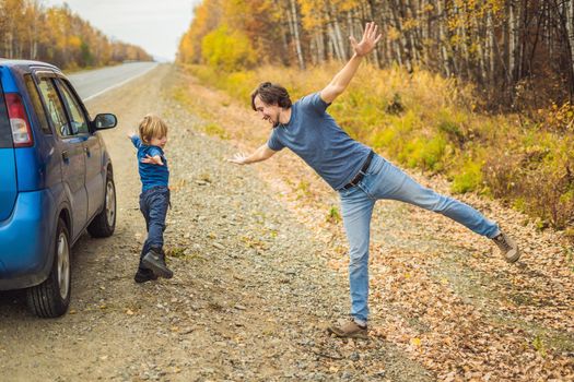 Dad and son are resting on the side of the road on a road trip. Road trip with children concept.