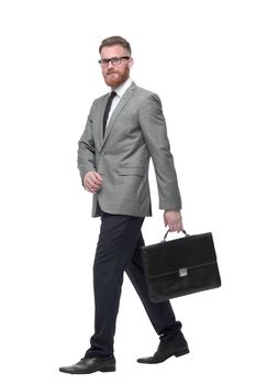 in full growth. a successful businessman with briefcase goes forward. isolated on white background