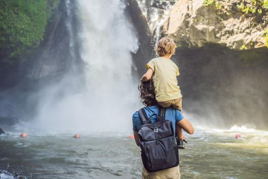 Dad and son tourists on the background of a waterfall. Traveling with kids concept. What to do with children Children friendly place.