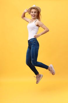 Happiness, dream, fun, joy, summer concept. Very excited happy cute caucasian teen is jumping up, in summer outfit, hat, on bright yellow background.