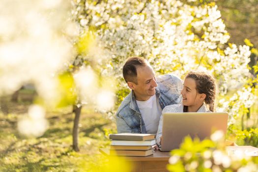 little girl with father studying on laptop outdoor.