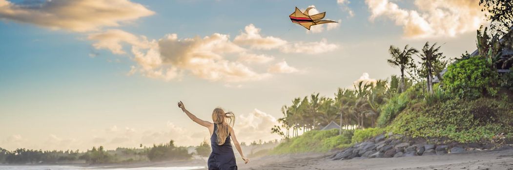 A young woman launches a kite on the beach. Dream, aspirations, future plans. BANNER, LONG FORMAT