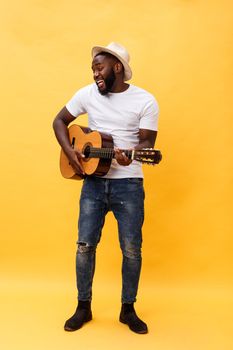 Full-length photo of excited artistic man playing his guitar. Isolated on yellow background